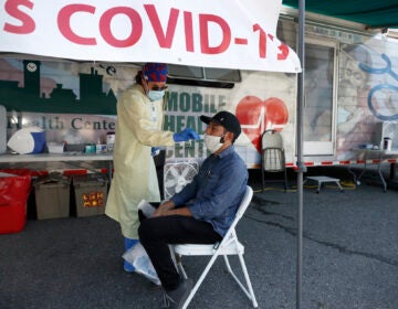 Nurse Tanya Markos administers a coronavirus test on patient Ricardo Sojuel at a mobile COVID-19 testing unit, Thursday, July 2, 2020, in Lawrence, Mass. (AP Photo/Elise Amendola)