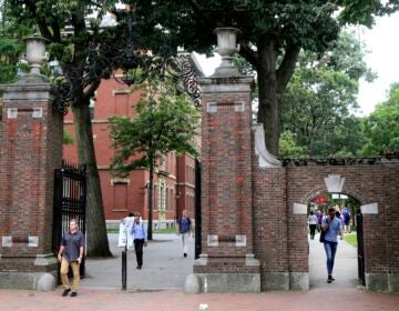FILE - In this Aug. 13, 2019, file photo, pedestrians walk through the gates of Harvard Yard at Harvard University in Cambridge, Mass. Harvard and the Massachusetts Institute of Technology filed a federal lawsuit Wednesday, July 8, 2020, challenging the Trump administration’s decision to bar international students from staying in the U.S. if they take classes entirely online this fall. Some institutions, including Harvard, have announced that all instruction will be offered remotely in the fall during the ongoing coronavirus pandemic. (AP Photo/Charles Krupa, File)