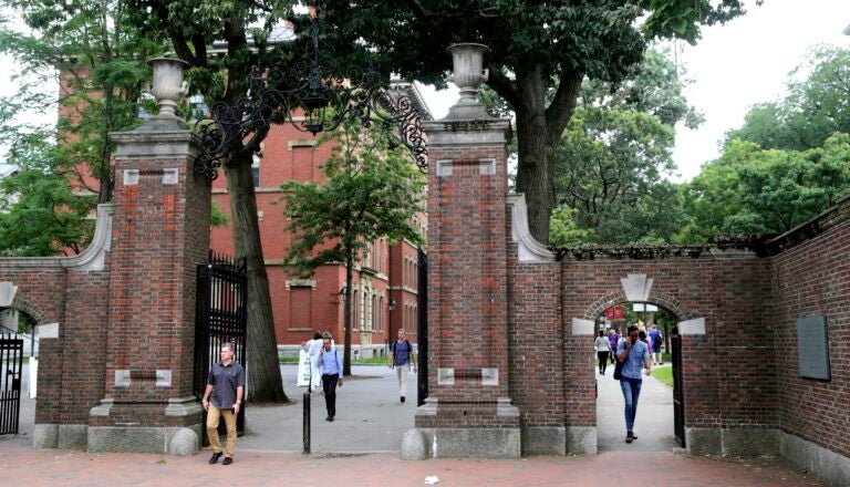 FILE - In this Aug. 13, 2019, file photo, pedestrians walk through the gates of Harvard Yard at Harvard University in Cambridge, Mass. Harvard and the Massachusetts Institute of Technology filed a federal lawsuit Wednesday, July 8, 2020, challenging the Trump administration’s decision to bar international students from staying in the U.S. if they take classes entirely online this fall. Some institutions, including Harvard, have announced that all instruction will be offered remotely in the fall during the ongoing coronavirus pandemic. (AP Photo/Charles Krupa, File)