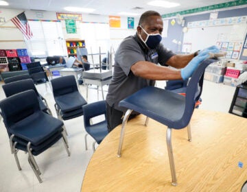Custodian Tracy Harris cleans chairs in a classroom at Brubaker Elementary School, Wednesday, July 8, 2020, in Des Moines, Iowa. (AP Photo/Charlie Neibergall)