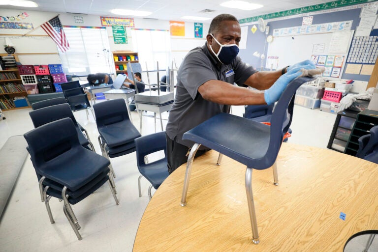 Custodian Tracy Harris cleans chairs in a classroom at Brubaker Elementary School, Wednesday, July 8, 2020, in Des Moines, Iowa. (AP Photo/Charlie Neibergall)