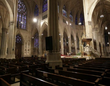 In this Sunday, April 12, 2020 file photo, Archbishop Timothy Dolan, right, delivers his homily over mostly empty pews as he leads an Easter Mass at St. Patrick's Cathedral in New York. (AP Photo/Seth Wenig)