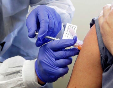 In this March 16, 2020, file photo, a subject receives a shot in the first-stage safety study clinical trial of a potential vaccine by Moderna for COVID-19, the disease caused by the new coronavirus, at the Kaiser Permanente Washington Health Research Institute in Seattle. (AP Photo/Ted S. Warren)
