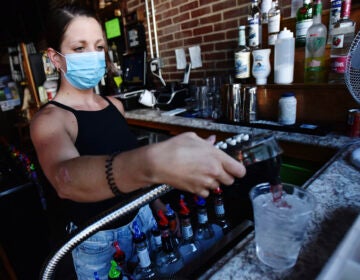 Bartender Kelsey Drozda makes a drink behind the bar at the Riverside Caf