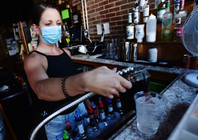 Bartender Kelsey Drozda makes a drink behind the bar at the Riverside Caf