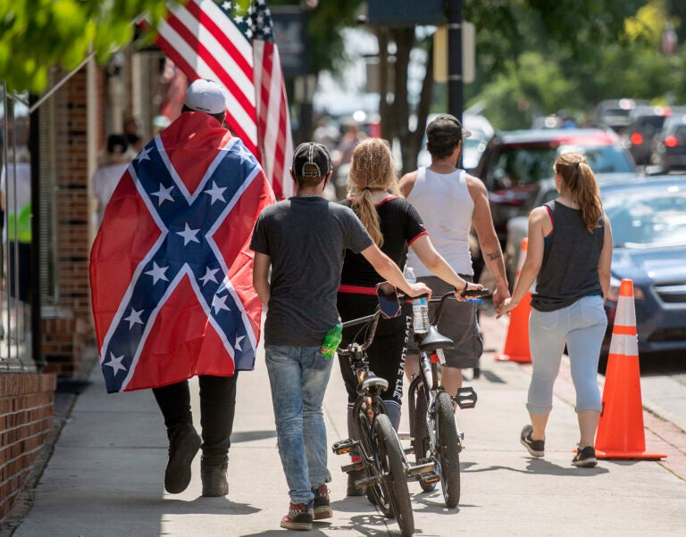 A young man wears a Confederate flag while walking with friends in Marion, VA Friday afternoon. (AP Photo/Andre Teague, Bristol Herald Courier)
