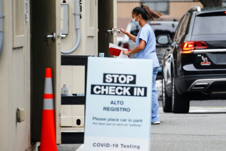 A medical worker collects a sample after a patient self-administered a COVID-19 nasal swab test at a Walgreens pharmacy, Friday, July 31, 2020, in Newark, N.J. (AP Photo/John Minchillo)