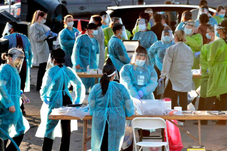 Medical personnel prepare to test hundreds of people lined up in vehicles