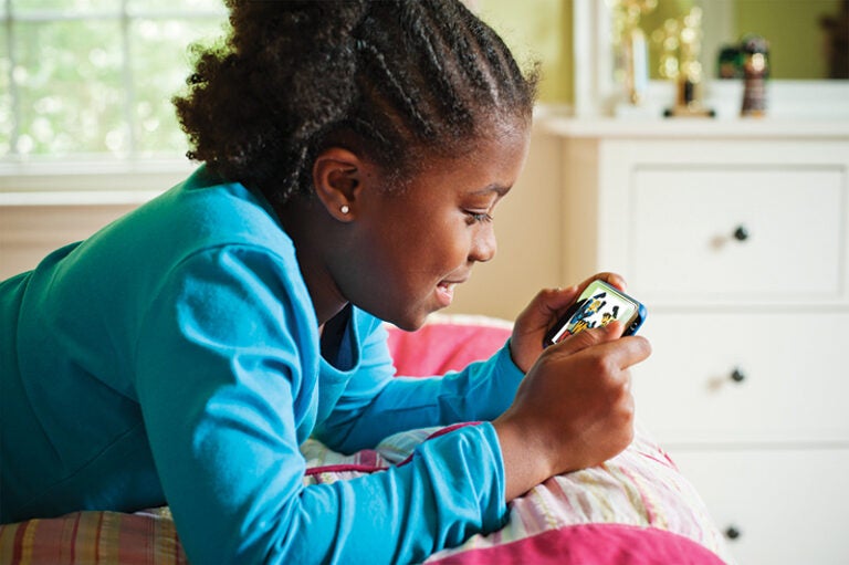 Krogh_100420_4461 A young girl watching an education video on her phone while she lies in bed