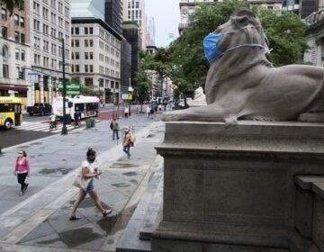 A face mask covers the mouth and nose of one of the iconic lion statues in front of the New York Public Library Main Branch on Wednesday, July 1, 2020, in New York, amid the coronavirus pandemic. (Ted Shaffrey/AP)