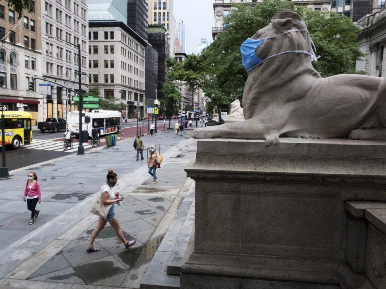 A face mask covers the mouth and nose of one of the iconic lion statues in front of the New York Public Library Main Branch on Wednesday, July 1, 2020, in New York, amid the coronavirus pandemic. (Ted Shaffrey/AP)