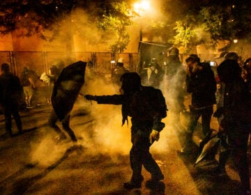 Protesters walk through chemical irritants deployed by federal agents in Portland, Ore. The inspector general of the Justice Department says he is investigating federal officers' roles in responding to protests in Portland and Washington, D.C. (Noah Berger/AP Photo)