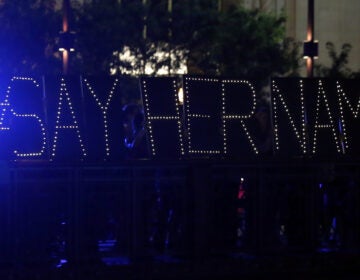 Protesters hold up a lighted sign reading 