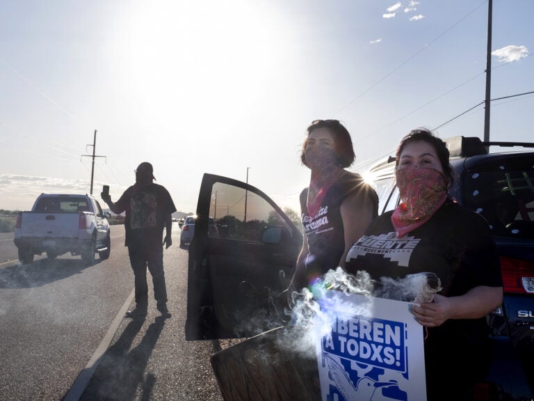 Demonstrators stand along the road in front of the La Palma Correctional Center in Eloy on April 10, 2020. The event was one of several car rallies calling for the release of immigrants detained at the ICE facility during COVID-19.