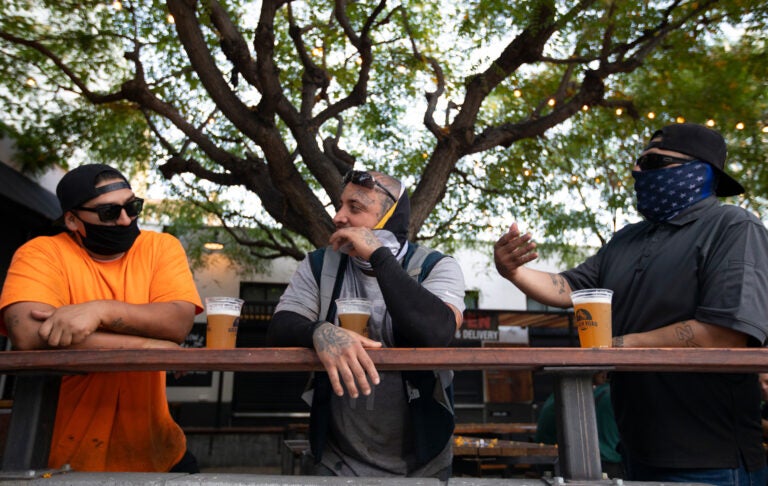 With new coronavirus infections climbing in most states, infectious disease experts are discouraging group get-togethers, especially those that involve drinking. In this photo patrons enjoy a beer outside the Central Market in Los Angeles, this week.
(Francine Orr/Los Angeles Times via Getty Images)