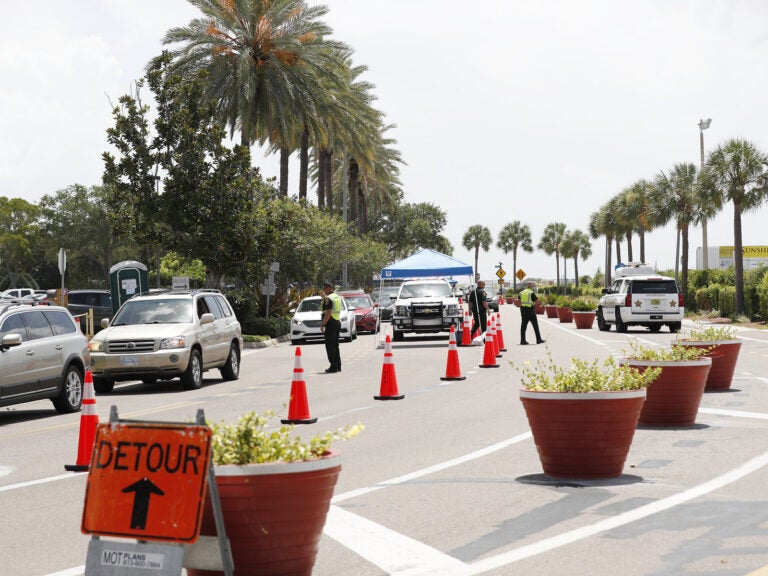 Cars line up for drive-through COVID-19 testing at the Duke Energy Center for the Arts Mahaffey Theater in St. Petersburg, Fla. The state reported a record-breaking 15,299 new cases on Sunday.