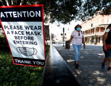 Visitors walk past face mask signs along Decatur Street