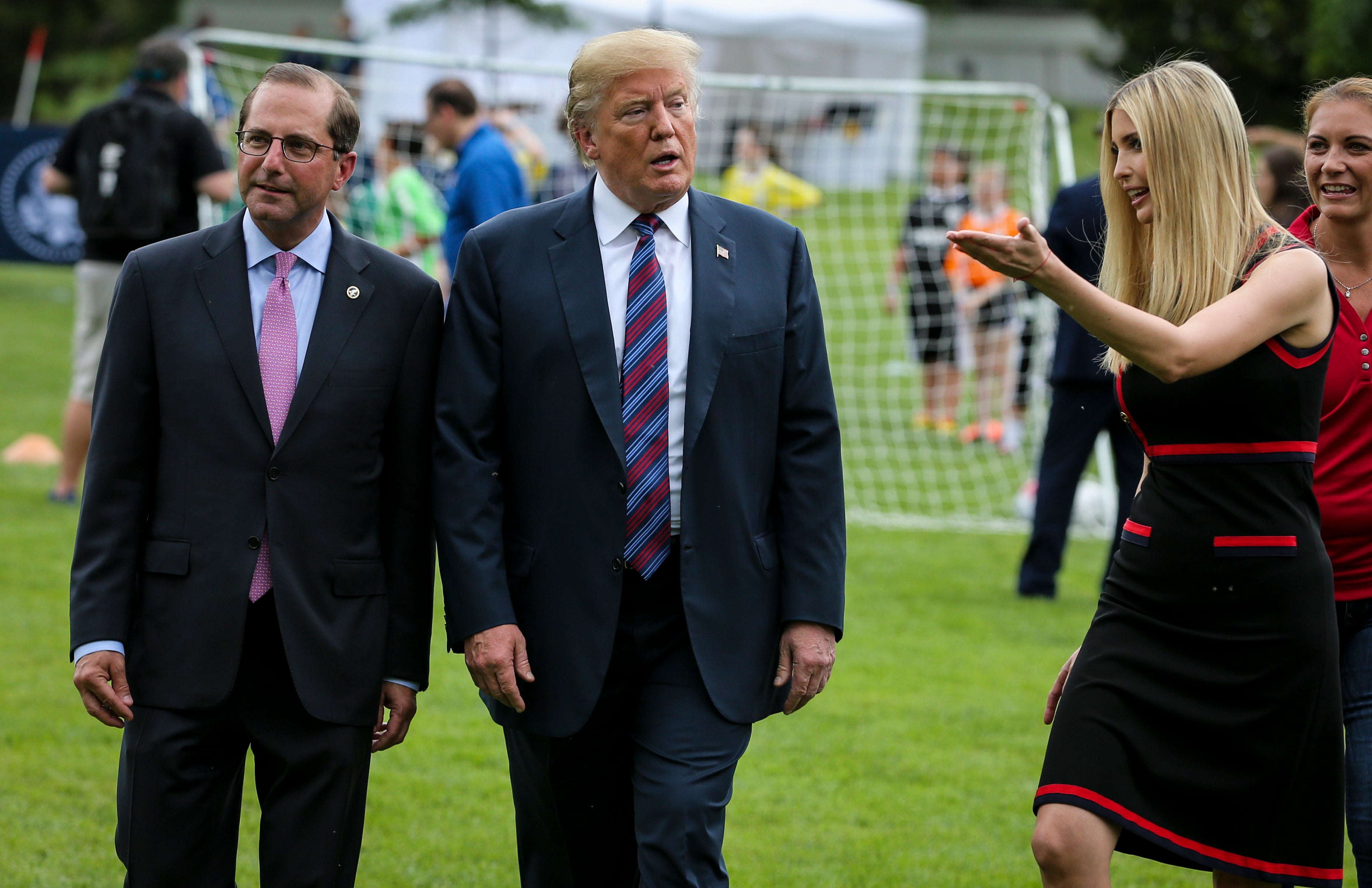 President Donald Trump, center, Health And Human Services Secretary Alex Azar, left, and Ivanka Trump, right, walk together on the South Lawn of the White House on May 30, 2018.