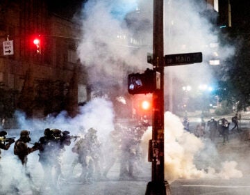 Federal agents use crowd control munitions to disperse Black Lives Matter protesters near the Mark O. Hatfield United States Courthouse on Monday, July 20, 2020, in Portland, Ore. Officers used teargas and projectiles to move the crowd after some protesters tore down a fence fronting the courthouse. (AP Photo/Noah Berger)