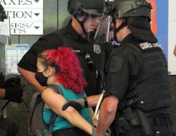 Police lead a protester away during a protest inside Philly's Municipal Services Building on June 23, 2020. (Emma Lee/WHYY)