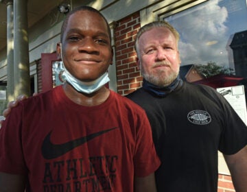 After discovering that the charges against him had been dropped, Timothy Cook shares a moment with The British Chip Shop owner Ian Whitfield in Haddonfield where he has been working parttime as a dishwasher for a year. (April Saul for WHYY)