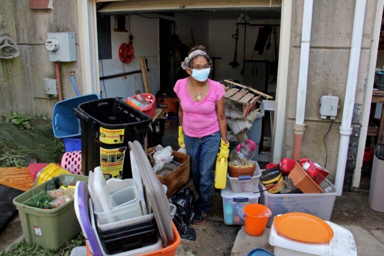 Yvette Palmer, 70, carries belongings out of the flooded first floor of her Eastwick home. (Emma Lee/WHYY)