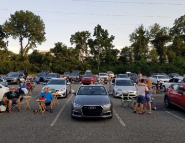 People and cars gathered at a parking lot turned into a drive-in during the coronavirus pandemic