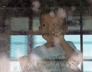 An immigrant child looks out from a U.S. Border Patrol bus as protesters block the street outside the U.S. Border Patrol Central Processing Center Saturday, June 23, 2018, in McAllen, Texas. (AP Photo/David J. Phillip)