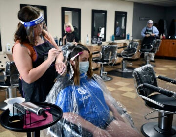 Salon Vizions stylist Michaela Slayton colors Paulette Fultz hair with Personal Protection Equipment on and Fultz wears a mask with a disposable gown on in Johnstown, Pa, Friday, June 5, 2020. (Todd Berkey/The Tribune-Democrat via AP)