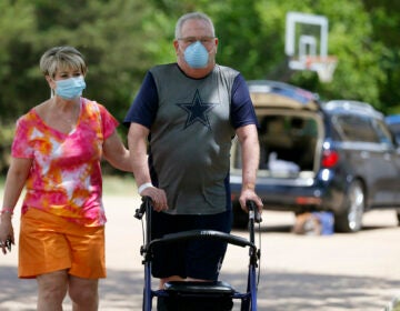 Terri Donelson, left, and her husband, Stephen, walk up their driveway to see friends and family awaiting him at his home in Midlothian, Texas on Friday, June 19, 2020, after his 90-day stay in the Zale Hospital on the UT Southwestern Campus. (AP Photo/Tony Gutierrez)