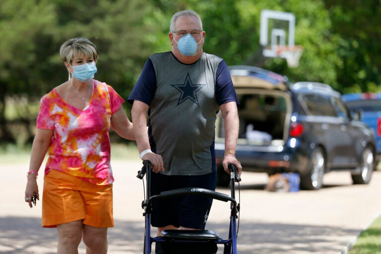 Terri Donelson, left, and her husband, Stephen, walk up their driveway to see friends and family awaiting him at his home in Midlothian, Texas on Friday, June 19, 2020, after his 90-day stay in the Zale Hospital on the UT Southwestern Campus. (AP Photo/Tony Gutierrez)