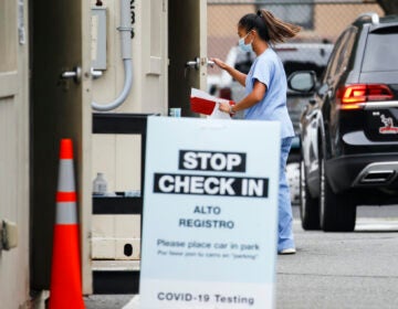 A medical worker collects a sample after a patient self-administered a COVID-19 nasal swab test at a Walgreens pharmacy, Friday, July 31, 2020, in Newark, N.J. (AP Photo/John Minchillo)