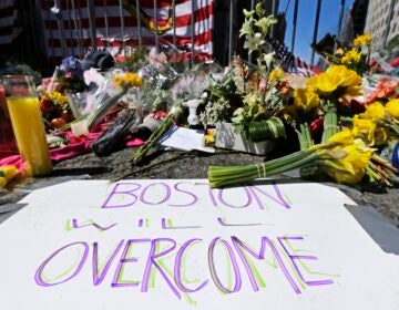 In this April 17, 2013 photograph, flowers and signs adorn a barrier, two days after two explosions killed three and injured hundreds, at Boylston Street near the of finish line of the Boston Marathon at a makeshift memorial for victims and survivors of the bombing. (AP Photo/Charles Krupa)