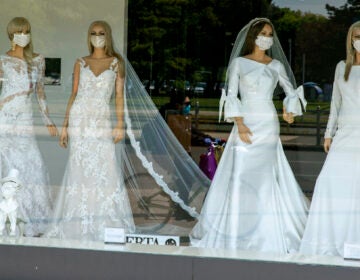 A cyclist wearing a coronavirus protective mask is reflected in a wedding dresses store window where mannequins also wear masks, in Zagreb, Croatia, Thursday, April 23, 2020. The store is closed because of Covid-19 lockdown. (AP Photo/Darko Bandic)