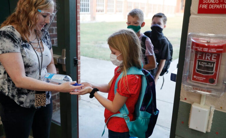 In this Aug. 5, 2020, file photo, wearing masks to prevent the spread of COVID-19, elementary school students use hand sanitizer before entering school for classes in Godley, Texas. (AP Photo/LM Otero)