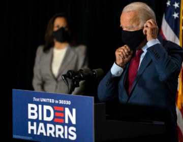 Democratic presidential candidate former Vice President Joe Biden joined by his running mate Sen. Kamala Harris, D-Calif., replaces his face mask after speaking at the Hotel DuPont in Wilmington, Del., Thursday, Aug. 13, 2020. (AP Photo/Carolyn Kaster)