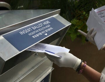 In this July 7, 2020 photo a woman drops off a mail-in ballot at a drop box in Hackensack, N.J. (AP Photo/Seth Wenig)