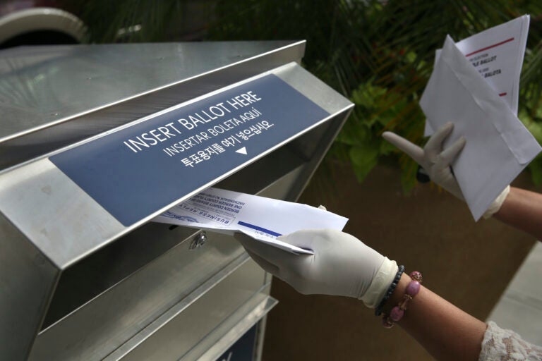 In this July 7, 2020 photo a woman drops off a mail-in ballot at a drop box in Hackensack, N.J. (AP Photo/Seth Wenig)