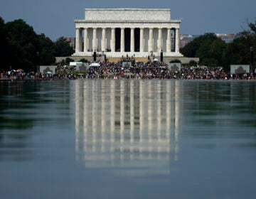 The Lincoln Memorial is reflected in the water as people gather to attend the March on Washington, Friday Aug. 28, 2020, in Washington, on the 57th anniversary of the Rev. Martin Luther King Jr.'s 