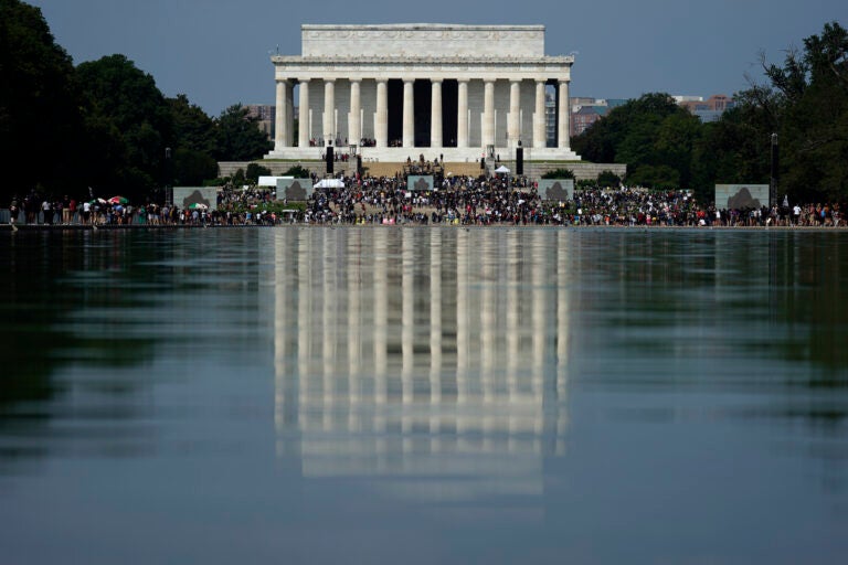 The Lincoln Memorial is reflected in the water as people gather to attend the March on Washington, Friday Aug. 28, 2020, in Washington, on the 57th anniversary of the Rev. Martin Luther King Jr.'s 