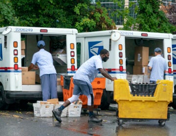 Letter carriers load mail trucks for deliveries at a U.S. Postal Service facility