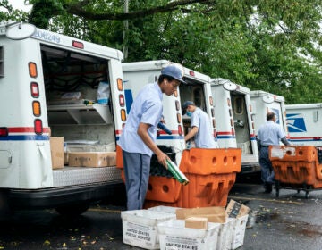 Letter carriers load mail trucks for deliveries at a U.S. Postal Service facility