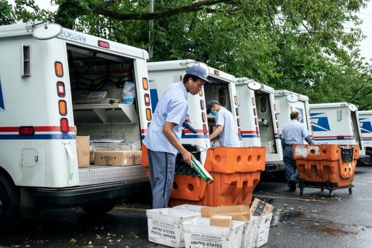 Letter carriers load mail trucks for deliveries at a U.S. Postal Service facility