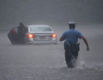 A Philadelphia police officer rushes to help a stranded motorist during Tropical Storm Isaias