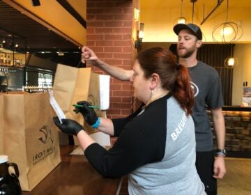 Moriah Guise and Dustin Mitchell check takeout orders at Iron Hill Brewery. (Cris Barrish/WHYY)