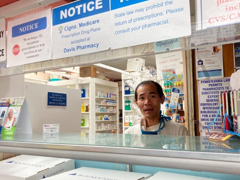 Pharmacist Steven Nguyen works at Davis Pharmacy on Baltimore Ave. He’s been calling the US Postal Service’s line for days trying to track down customer packages (Hannah Chinn/WHYY) 