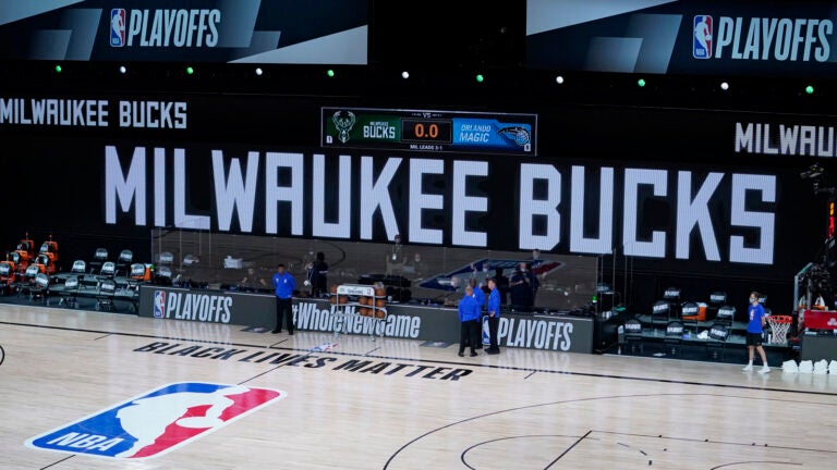 Officials stand beside an empty court at the scheduled start of an NBA basketball playoff game between the Milwaukee Bucks and the Orlando Magic, Wednesday in Lake Buena Vista, Fla. The Bucks didn't take the floor in protest against racial injustice and the shooting of Jacob Blake, a Black man, by police in Kenosha, Wisconsin.