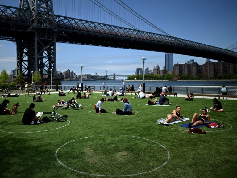 A new study has found that parks in low-income and majority nonwhite communities are smaller and serve a larger number of people per park acre. People are seen here relaxing in May in Brooklyn's Domino Park.
(Johannes Eisele/AFP via Getty Images)