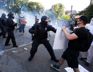 A law enforcement officer raises a baton and tear gas is fired during protests near the White House on June 1. (Jose Luis Magana/AFP via Getty Images)