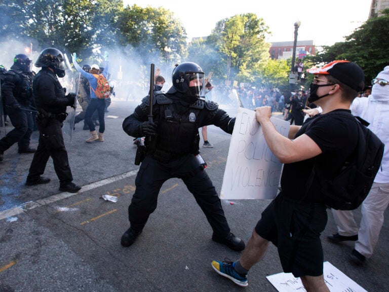 A law enforcement officer raises a baton and tear gas is fired during protests near the White House on June 1. (Jose Luis Magana/AFP via Getty Images)